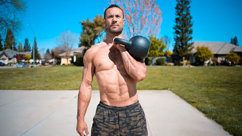 Single-arm kettlebell front rack hold demonstrating proper form for kettlebell rack and suitcase carries, engaging obliques and core stability