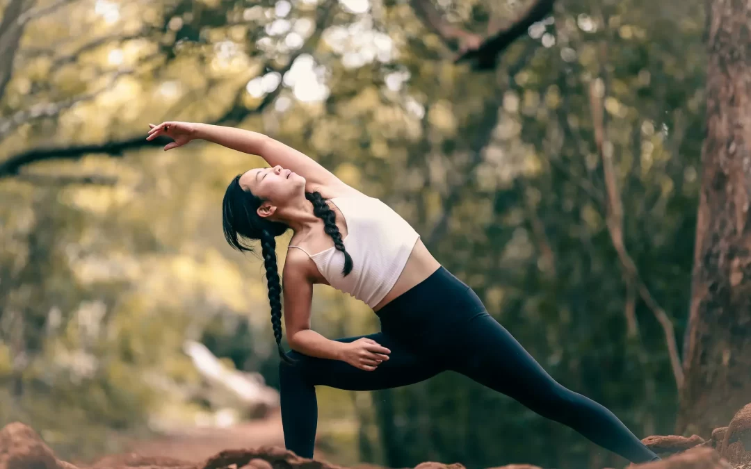 Woman practicing active stretching for fitness outdoors in a yoga side angle pose, surrounded by nature.